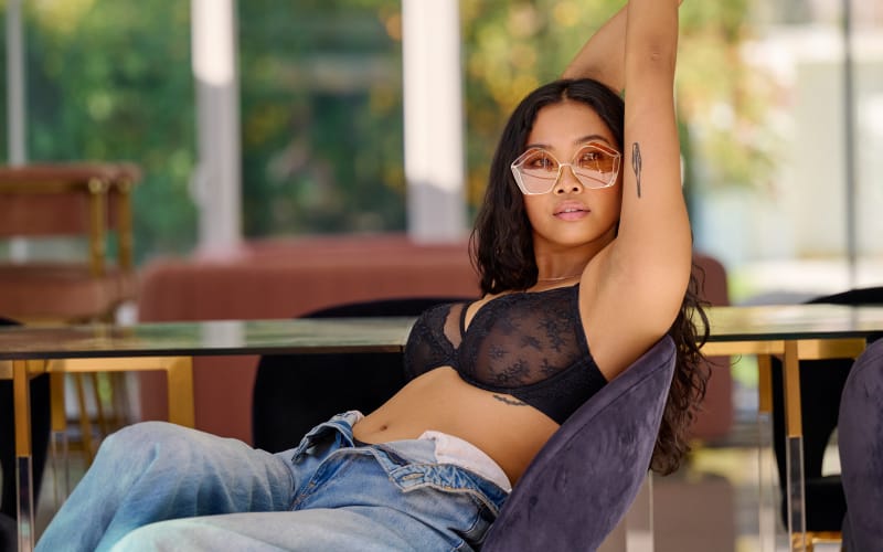Reclining woman in a Camio Mio bra, jeans, and sunglasses